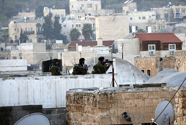 Soldados israelenses observam protesto contra Israel no domingo (31) em Hebron, na Cisjordnia
