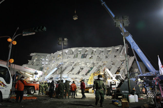 l work at the site of a collapsed building in the southern Taiwanese city of Tainan early on February 7, 2016 following a strong 6.4-magnitude earthquake. More than 250 people have been rescued from the Wei-kuan apartment complex in the southern city of Tainan since the quake hit at 4:00 am Saturday, killing 14 people and toppling four blocks of around 100 homes in total. / AFP / ANTHONY WALLACE