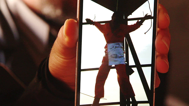 Líbio mostra no celular imagem de seu irmão, que teria sido morto a tiros e crucificado pelo EI 