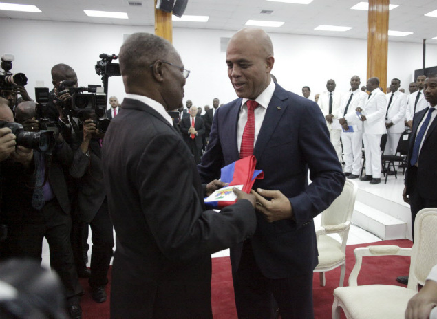 Martelly ( dir.) entrega a faixa presidencial ao presidente do Senado, Jocelerme Privert, neste domingo (7)