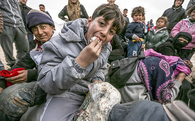 Refugiados srios dividem comida na fronteira com a Turquia; passagem entre os pases est fechada h 4 dias 