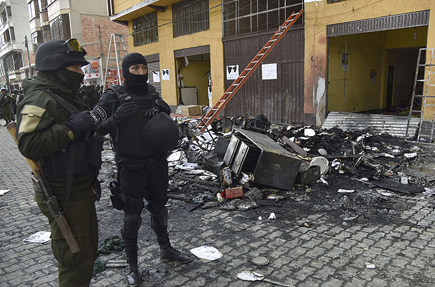 Police stabd by damage caused by demonstrators on the city hall of El Alto, 12 km from La Paz, on February 17, 2016. Six people died from smoke inhalation when a crowd set fire to a city hall in Bolivia Wednesday in a dispute linked to a corruption scandal, officials said. AFP PHOTO/Aizar Raldes ORG XMIT: BOL910