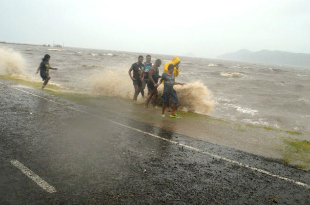 People are splashed by a wave whipped up by the encroaching cyclone Winston in Labasa, Fiji, Saturday, Feb. 20, 2016. The Pacific island nation of Fiji is hunkering down as a formidable cyclone with winds of 300 kilometers (186 miles) per hour approaches. (Luke Rawalai/Fiji Times via AP) EDITORIAL USE ONLY, FIJI OUT ORG XMIT: SYD801