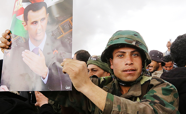 Voluntrios srios celebram, com imagens de Assad, fim de um treinamento paramilitar no norte de Damasco