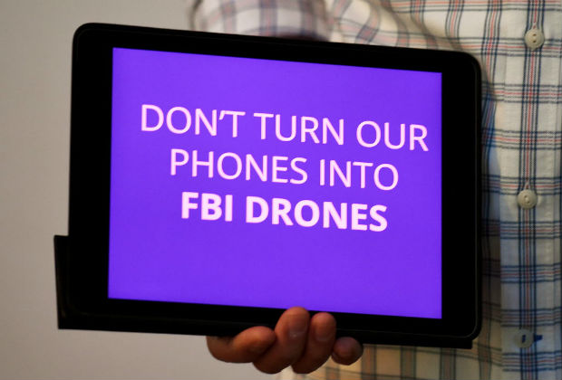 Manifestante mostra iPad com frase "no transforme nossos telefones em drones do FBI"