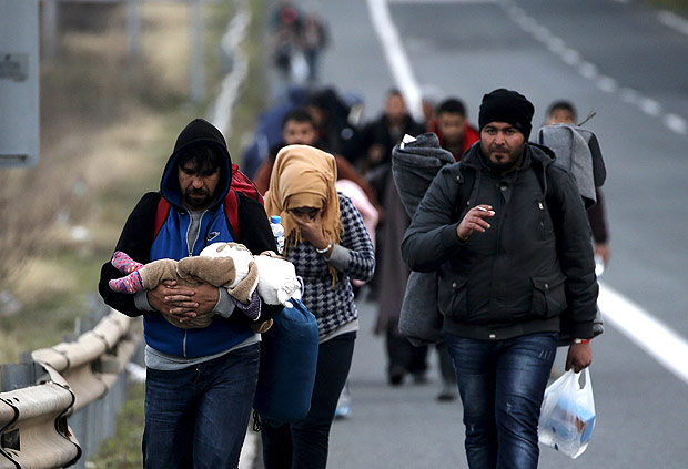 Refugiados levam suas famlia em estrada grega, perto da Macednia, apesar de fechamento da fronteira