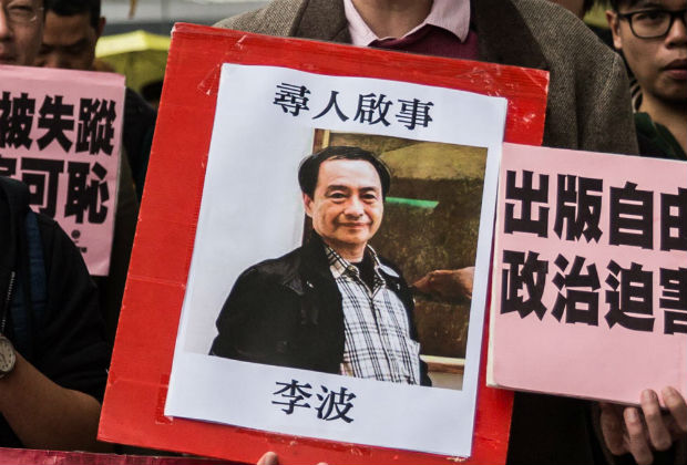 In this file picture taken on January 3, 2016, a protestor holds up a missing person notice for Lee Bo, 65, the latest of five Hong Kong booksellers from the same Mighty Current publishing house to go missing, as they walk towards China's Liaison Office in Hong Kong. Britain said February 12, 2016 a Hong Kong bookseller believed detained by China was "involuntarily removed to the mainland", in its strongest comments yet on a case that has rocked the city amid fears its promised freedoms are being eroded. AFP PHOTO / ANTHONY WALLACE / FILES ORG XMIT: ACW001