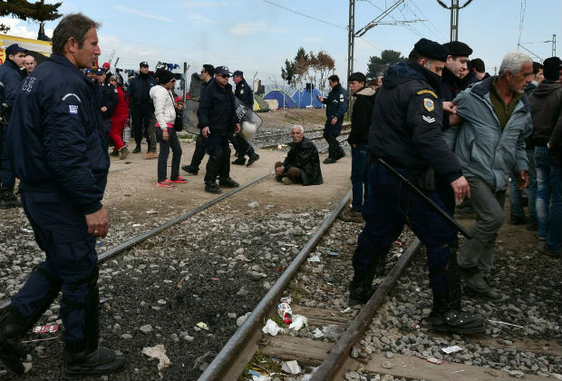 Police forces try to disperse refugees staging a protest on rail tracks, blocking a train coming from Macedonia, as they call for the opening of the borders at the overcrowded makeshift camp at the Greece-Macedonia border near the Greek village of Idomeni, on March 3, 2016, where thousands of people are stranded. / AFP / LOUISA GOULIAMAKI ORG XMIT: LOU4963