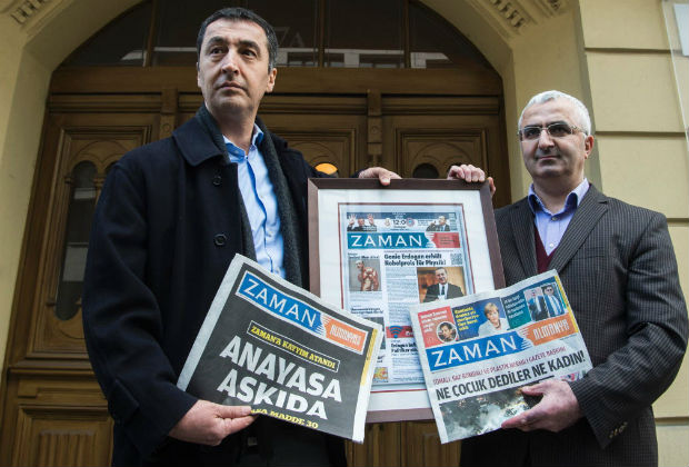 Chief editor of the German edition of Turkish daily Zaman, Suleyman Bag (R) and German Green Party co-leader Cem Oezdemir pose with the newspaper's last edition (from March 5, 2016) which includes material from the Turkish national edition (L), a German parody edition (C), and the new Germany edition (L), outside his office in Berlin on March 7, 2016. Turkish police seized control on March 4, 2016 of the top-selling newspaper, which opposes President Recep Tayyib Erdogan, drawing condemnation from the European Union, the United States and Russia, as well as international media watchdogs. / AFP / John MACDOUGALL