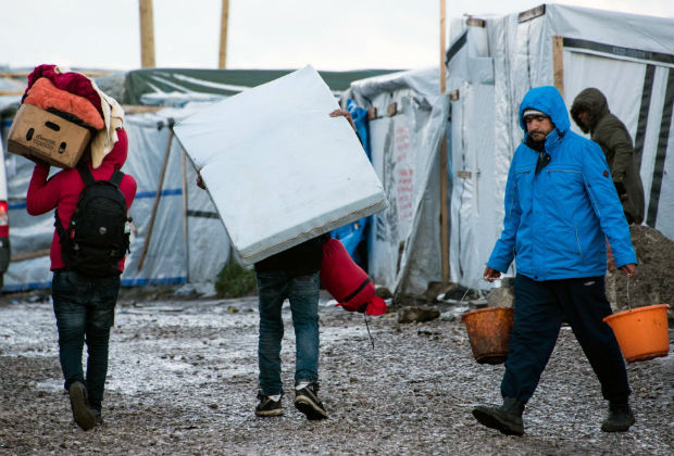 Men carry their belongings after been evicted during the dismantling of the southern part of the so-called 'Jungle' migrant camp in Calais, northern France, on March 7, 2016. A second week of demolition was underway on March 7, 2016 in the Calais migrant camp known as the "Jungle" while France's first international-standard refugee camp was set to open further along the coast. / AFP / DENIS CHARLET ORG XMIT: LIL646
