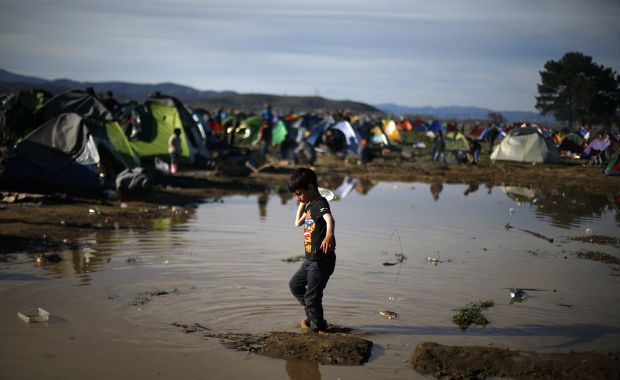  boy carries a bottle of water as he walks through mud waiting to cross the Greek-Macedonian border, at a makeshift camp for migrants near the village of Idomeni, Greece March 8, 2016. REUTERS/Stoyan Nenov ORG XMIT: STN100