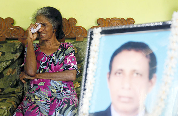 Magret Fernando cries next to an image of her husband Niculas Fernando, who died at the Tokyo Regional Immigration Bureau, in Chilaw November 10, 2015. To match Special Report JAPAN-DETENTION/ REUTERS/Dinuka Liyanawatte SEARCH 