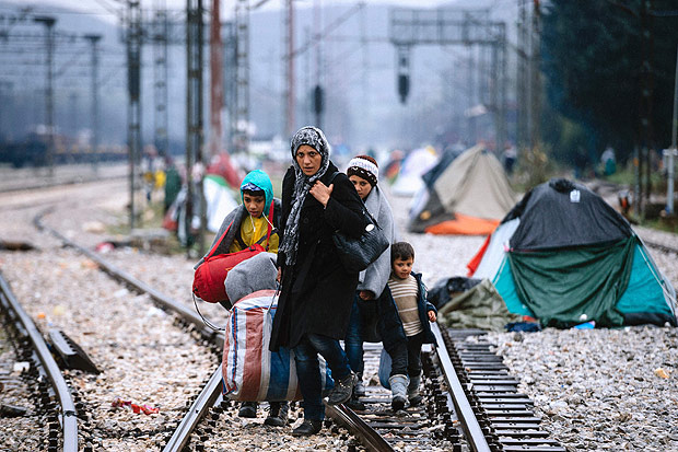 A woman and three children walk on railway tracks connecting Greece with western Europe at the Greek-Macedonian border near the Greek village of Idomeni on March 9, 2016, where thousands of refugees and migrants are trapped by the Balkan border blockade. The main migrant trail from Greece to northern Europe was blocked March 9 after western Balkan nations slammed shut their borders, hiking pressure for an EU-Turkey deal and exacerbating a dire situation on the Macedonian border. More than 14,000 mainly Syrian and Iraqi refugees are camping out by the northern Idomeni border crossing with Macedonia -- many of them for weeks -- at a muddy, unhygienic camp operated by beleaguered aid groups. / AFP / DIMITAR DILKOFF ORG XMIT: DIM035