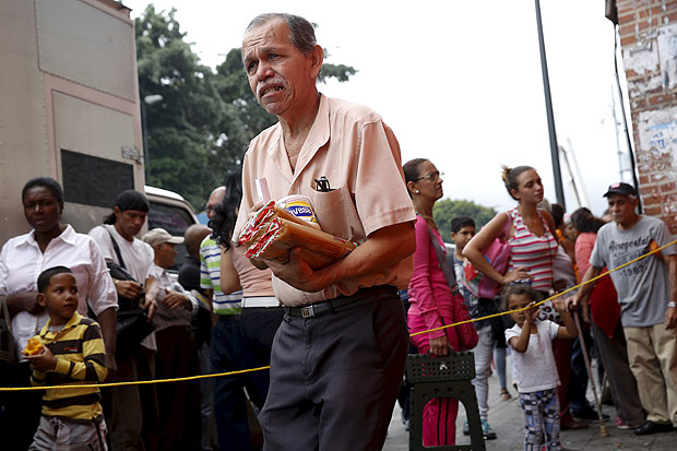 Homem carrega nas mos compra feita em mercado de Caracas; Venezuela sofre desabastecimento