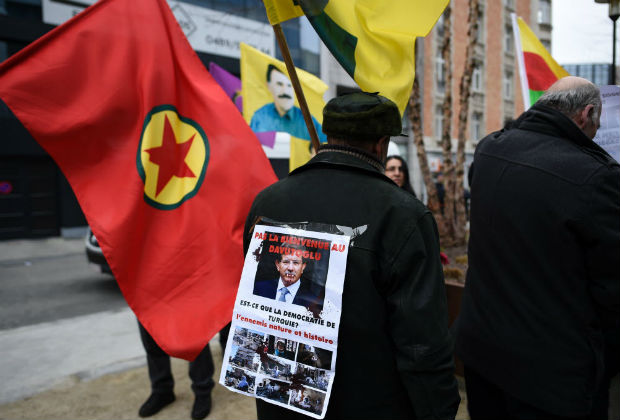 Kurdish people hold Kurdistan Workers' Party flag and placards depicting Turkish leaders as they take part in a protest to call for an end of the Turkish State terror in Kurdistan, during the European Union summit in Brussels on March 18, 2016. Underscoring tension with Brussels, Turkish President Recep Tayyip Erdogan accused the Europeans of supporting the outlawed Kurdistan Workers' Party (PKK) days after a bombing in Ankara claimed by Kurdish rebels that killed 35 people. Many European Union states have expressed concerns about Ankara's human rights record, including its treatment of the Kurds and a crackdown on critics of the government. The United Nations and rights groups fear the deal could violate international law that forbids the mass deportation of refugees. / AFP PHOTO / JOHN THYS ORG XMIT: THY01