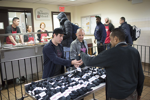 -- PHOTO MOVED IN ADVANCE AND NOT FOR USE - ONLINE OR IN PRINT - BEFORE MARCH 20, 2016. -- Bombas co-founders Randy Goldberg, left, and David Heath pass out their companys socks during lunch at The Bowery Mission in New York, Feb. 29, 2016. Bombas gives a pair of socks to a homeless person for every pair it sells, joining a growing list of buy one, give one companies. (Kevin Hagen/The New York Times) ORG XMIT: XNYT31 ***DIREITOS RESERVADOS. NO PUBLICAR SEM AUTORIZAO DO DETENTOR DOS DIREITOS AUTORAIS E DE IMAGEM***