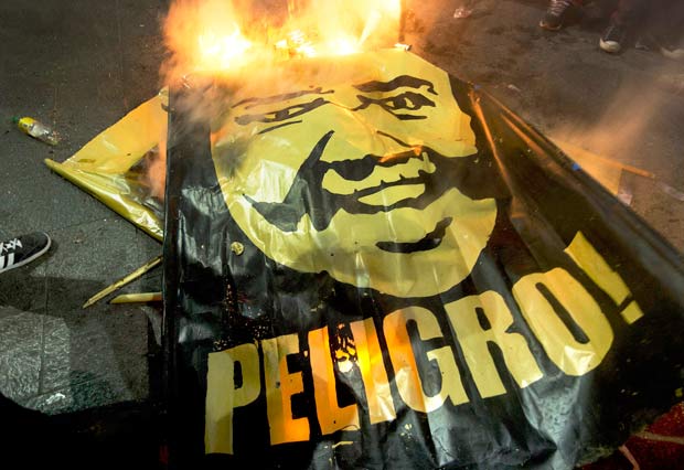 Bandeira com a mensagem "Perigo" e a foto de Keiko Fujimori  queimada em protesto em Lima