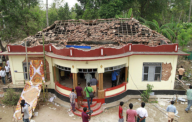 People gather around a damaged section of a temple after a fire broke out at a temple in Kollam in the southern state of Kerala, India, April 10, 2016. A huge fire swept through a temple in India's southern Kerala state early on Sunday (April 10), killing nearly 80 people and injuring over 200 gathered for a fireworks display to mark the start of the local Hindu new year. REUTERS/Sivaram V TPX IMAGES OF THE DAY ORG XMIT: DEL202