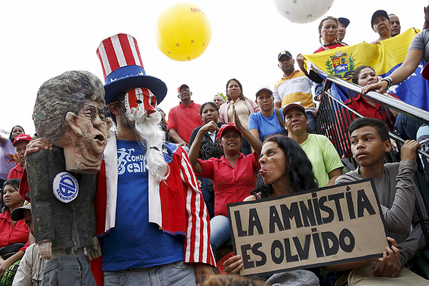 A supporter of Venezuela's President Nicolas Maduro carrying a placard that reads, "Amnesty is forgetting", gestures to a man carrying a doll depicting Henry Ramos Allup (L), President of the National Assembly, during a rally against the opposition's amnesty law at Miraflores Palace in Caracas, April 7, 2016. REUTERS/Carlos Garcia Rawlins TPX IMAGES OF THE DAY ORG XMIT: VEN07