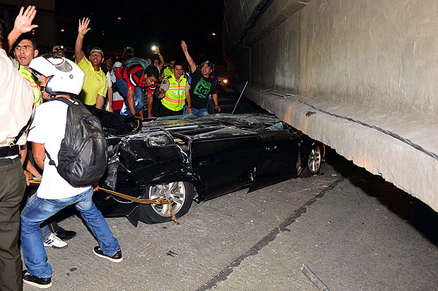 Voluntários tentam tirar mulher de carro esmagado por um viaduto de Guayaquil, que caiu em terremoto