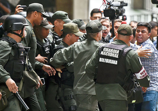 Venezuelan opposition congress members confront National Guard members in front of the National Electoral Council in Caracas on April 21, 2016. 2016. AFP PHOTO A group of Venezuelan opposition deputies chained Thursday at the headquarters of the electoral body to demand the activation of a recall referendum against President Nicolas Maduro, a claim that also led college students to start a hunger strike. / AFP PHOTO / JUAN BARRETO