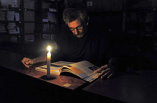 Homem usa uma vela para ler durante o apago dirio programado para San Cristbal, na Venezuela