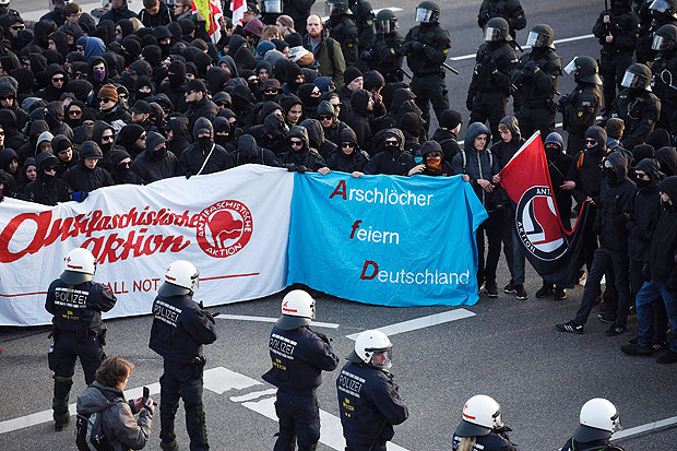 Manifestantes carregam faixa com dizeres "Arschloecher feiern Deutschland", algo como partido dos cretinos da Alemanha, em protesto contra o partido AfD em Stuttgart 