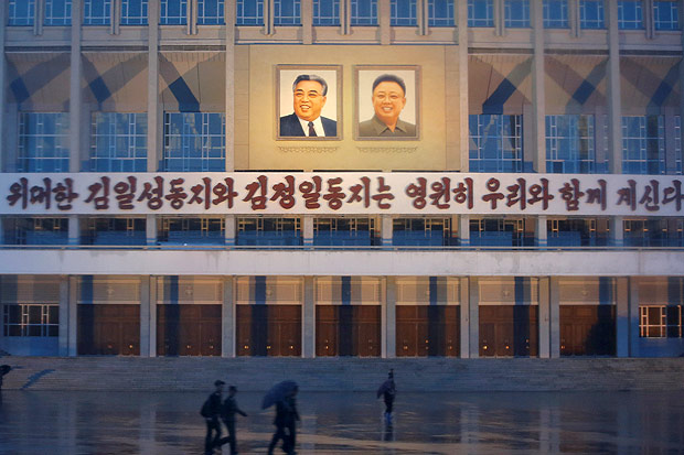 People pass in front of the building decorated with slogan "The great comrades Kim Il Sung and Kim Jong Il will be with us forever" and their pictures in central Pyongyang, North Korea May 3, 2016. REUTERS/Damir Sagolj TPX IMAGES OF THE DAY ORG XMIT: DSP01