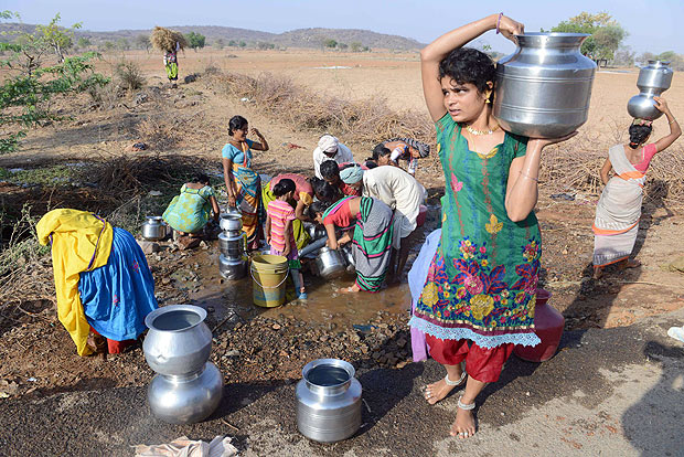 Moradores de vila indiana transportam gua coletada em fonte em regio atingida pela seca