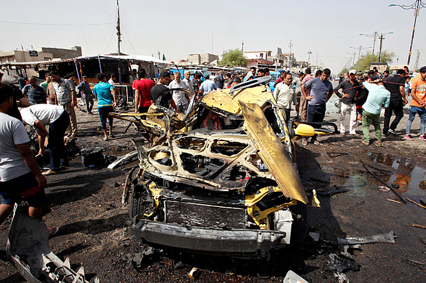 Carro destruído por explosão em atentado em mercado de Bagdá