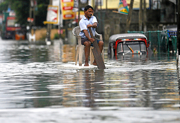 A man sits on a chair as he uses a piece of styrofoam to move through a flooded road in Wellampitiya, Sri Lanka May 21, 2016. REUTERS/Dinuka Liyanawatte ORG XMIT: GGGCOL06