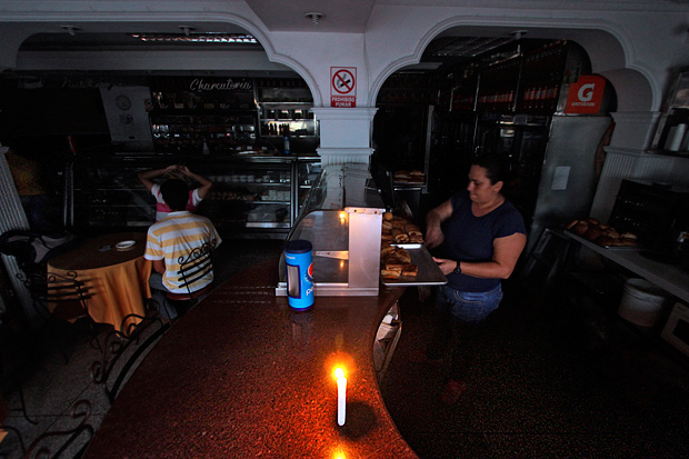 A woman works at a bakery during a power cut in the border state of San Cristobal, 600 km west of Caracas on April 25, 2016. Recession-hit Venezuela will turn off the electricity supply in its 10 most populous states for four hours a day for 40 days to deal with a severe power shortage, the government said Thursday. / AFP PHOTO / GEORGE CASTELLANOS