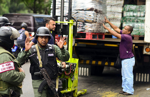 Venezuelas National police members stand guard outside a supermarket while people line up to buy basic food and household items in the poor neighborhood of Lidice, in Caracas, Venezuela on May 27, 2016. President Nicolas Maduro announced a process of "review and correction," including combating corrupt practices, following his party's crushing defeat in parliamentary elections in December. / AFP PHOTO / RONALDO SCHEMIDT ORG XMIT: RSA269