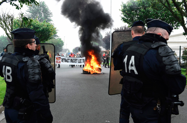 French riot police stand in front of French CGT union's members next to tires on fire during a protest against the government's planned labour law reforms at the Simmons factory in Saint Amand les Eaux, northern France on May 31, 2016 during a visit of the French Economy Minister. / AFP PHOTO / FRANCOIS LO PRESTI ORG XMIT: 1647
