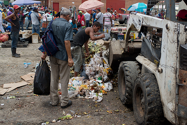Junto a cães e máquinas, venezuelanos reviram lixo da feira de Coche, em Caracas, em busca de comida