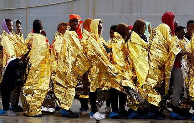 Grupo de refugiados e imigrantes desembarca de um navio italiano no porto de Augusta, na Sicília