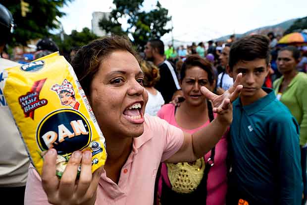 Moradora de Caracas grita com policiais em fila para comprar produtos bsicos em um supermercado