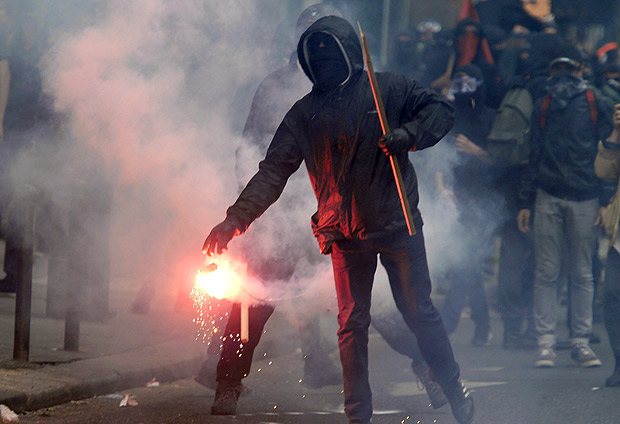 Manifestante mascarado carrega sinalizador durante um protesto contra a reforma trabalhista em Paris