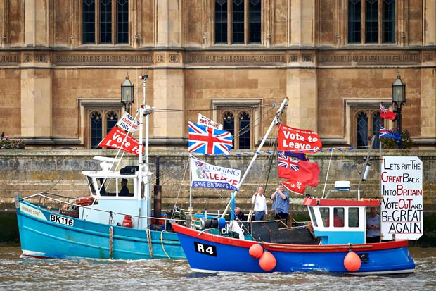 Boatsd decorated with flags and banners from the 'Fishing for Leave' group that are campaigning for a 'leave' vote in the EU referendum sail by the British Houses of Parliament as part of a "Brexit flotilla' on the river Thames in London on June 15, 2016. A Brexit flotilla of fishing boats sailed up the River Thames into London today with foghorns sounding, in a protest against EU fishing quotas by the campaign for Britain to leave the European Union. / AFP PHOTO / NIKLAS HALLE'N