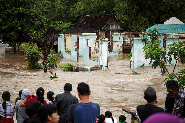 People stand in front of a flooded area in Kampung Sewuresidential area in Solo, Central Java province, Indonesia, June 19, 2016. Antara Foto/Maulana Surya/via REUTERS ATTENTION EDITORS - THIS IMAGE WAS PROVIDED BY A THIRD PARTY. FOR EDITORIAL USE ONLY. MANDATORY CREDIT. INDONESIA OUT. THIS PICTURE WAS PROCESSED BY REUTERS TO ENHANCE QUALITY. AN UNPROCESSED VERSION HAS BEEN PROVIDED SEPARATELY. TPX IMAGES OF THE DAY ORG XMIT: BEA01R