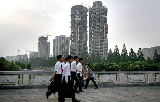 In this June 27, 2016, photo, North Korean men and women walk past buildings under construction on "Ryomyong Street," in Pyongyang, North Korea. Hoping to show the world his country is doing just fine despite sanctions and outside pressure over its nuclear weapons program, North Korean leader Kim Jong Un has put his soldier-builders to work on yet another major project - a series of apartments and high-rises that are once again changing the Pyongyang skyline. "Ryomyong Street," is to have the country's tallest apartment building, at 70 stories, along with a 50-story building and a handful of smaller ones in the 30-40 story range. (AP Photo/Wong Maye-E) ORG XMIT: XWM101