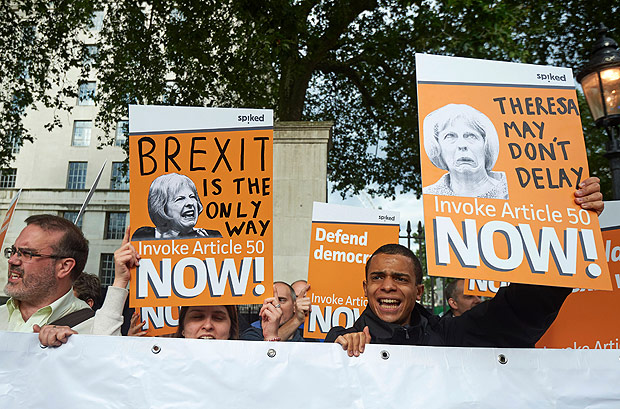 Manifestantes seguram cartazes pedindo  nova premi britnica, Theresa May, que continue o 'brexit'