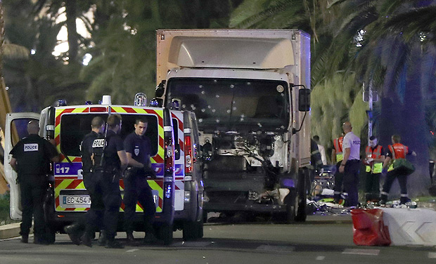 Police officers and rescued workers stand near a van that ploughed into a crowd leaving a fireworks display in the French Riviera town of Nice on July 14, 2016. The mayor of the French city of Nice said dozens of people were likely killed after a van rammed into a crowd marking Bastille Day in the French Riviera resort today and urged residents to stay indoors. / AFP PHOTO / VALERY HACHE ORG XMIT: VH20199