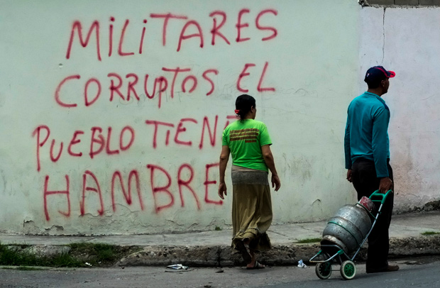 A inscription on a wall in the low income Santa Rita neighborhood in Maracay, 70km from Caracas, reads "Corrupt military, the people is hungry", on July 21, 2016. Long lines, chronic shortages, hyperinflation and violent crime have left President Nicolas Maduro fighting for his political life. / AFP PHOTO / JUAN BARRETO
