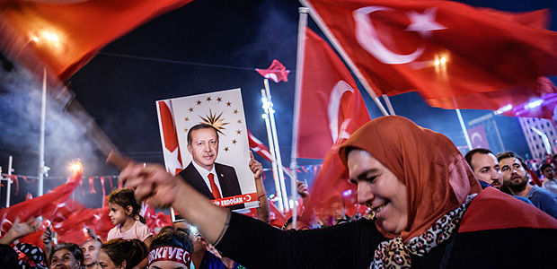 Pro-Erdogan supporters hold Turkish national flags and a portrait of Turkish President Recep Tayyip Erdogan during a rally against the military coup on Taksim square in Istanbul on July 23, 2016. Turkey pushed on with a sweeping crackdown against suspected plotters of its failed coup, defiantly telling EU critics it had no choice but to root out hidden enemies. Using new emergency powers, President Recep Tayyip Erdogan's cabinet decreed that police could now hold suspects for one month without charge, and also announced it would shut down over 1,000 private schools it deems subversive. / AFP PHOTO / OZAN KOSE ORG XMIT: 7875