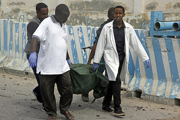 United Nations office guards carry the dead body of their colleague, who was killed in a suicide car bomb, outside the UN's office in Mogadishu, Somalia, Tuesday, July 26, 2016. A suicide bomber detonated an explosives-laden car outside the United Nations Mine Action Service offices in Mogadishu, killing 13 people, including seven U.N. guards, a Somali police official said. (AP Photo/Farah Abdi Warsameh) ORG XMIT: AAS101