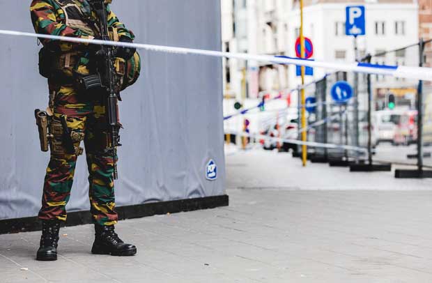 An armed soldier stands behind a cordon in central Brussels on July 20, 2016, during a police intervention to surround a "suspect" individual. Police backed by bomb disposal teams on July 20 cordoned off part of central Brussels where they surrounded a "suspect" individual wearing a long coat with wires showing. "Following police intervention, a cordon has been established" around part of the Place de la Monnaie and adjoining streets, Brussels police said in a tweeted message. / AFP PHOTO / Belga / SISKA GREMMELPREZ / Belgium OUT