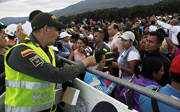 Policial colombiano e milhares de venezuelanos na fronteira entre os pases em Cucuta, na Colmbia