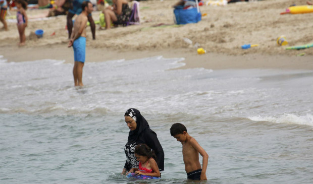 Vestida com o 'burquni', mulher muulmana leva seus filhos para nadarem em praia de Marselha
