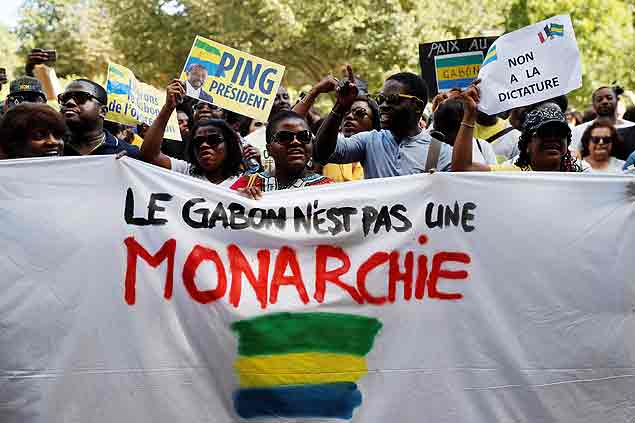People protest behind a banner reading "Gabon is not a monarchy" during a demonstration in support of the Gabonese people, at the Esplanade du Trocadero in Paris, on September 3, 2016. In the background, the Eiffel tower is seen. Post-election violence in Gabon has claimed two more lives, sources said on September 3, 2016, after President Ali Bongo was proclaimed winner of last week's vote while main challenger Jean Ping claimed victory for himself. Such claims have not been independently verified, but according to an AFP count the latest deaths bring the recent death toll to seven. Bongo was declared victorious by a razor-thin margin of just under 6,000 votes, but his main challenger Ping, a veteran diplomat and former top African Union official, has insisted the vote was rigged and on September 3 claimed victory for himself. / AFP PHOTO / THOMAS SAMSON ORG XMIT: 3049
